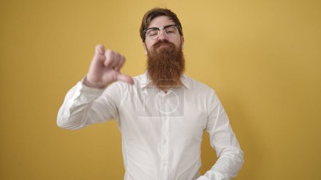 Photo for Young redhead man doing negative gesture with thumb down over isolated yellow background - Royalty Free Image
