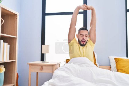 Téléchargez les photos : Young latin man waking up stretching arms yawning at bedroom - en image libre de droit