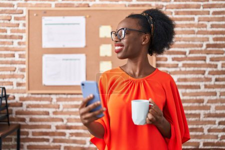 Téléchargez les photos : African american woman business worker using smartphone drinking coffee at office - en image libre de droit