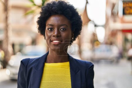 Téléchargez les photos : Jeune femme afro-américaine cadre d'affaires souriant confiant à la rue - en image libre de droit