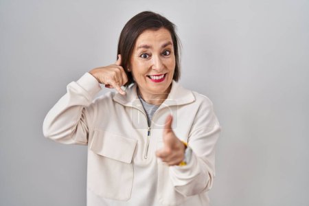 Photo for Middle age hispanic woman standing over isolated background smiling doing talking on the telephone gesture and pointing to you. call me. - Royalty Free Image