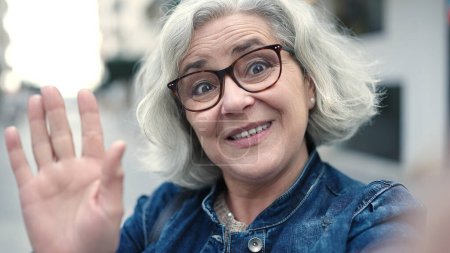 Téléchargez les photos : Middle age woman with grey hair smiling confident having video call at street - en image libre de droit