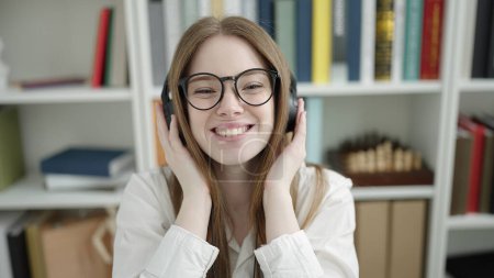 Téléchargez les photos : Young blonde woman student smiling confident listening to music at university classroom - en image libre de droit