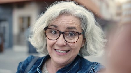 Téléchargez les photos : Middle age woman with grey hair smiling confident having video call at street - en image libre de droit