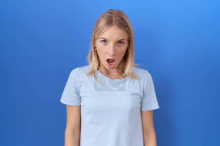 Téléchargez les photos : Jeune femme caucasienne portant T-shirt bleu décontracté dans le visage de choc, l'air sceptique et sarcastique, surpris avec la bouche ouverte - en image libre de droit