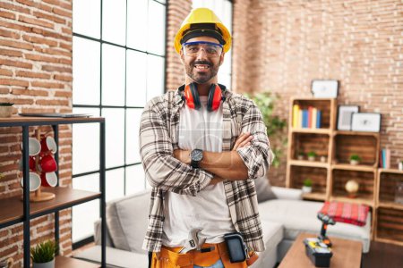 Téléchargez les photos : Jeune homme hispanique travailleur souriant confiant debout avec les bras croisés geste à la maison - en image libre de droit