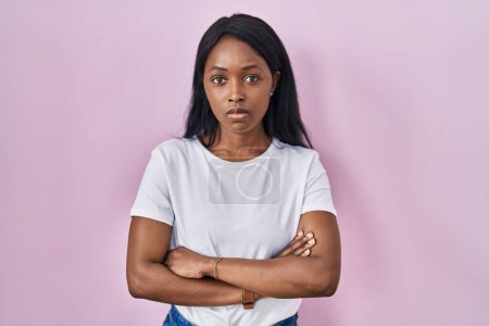 Téléchargez les photos : Jeune femme africaine portant t-shirt blanc décontracté sceptique et nerveux, expression désapprobatrice sur le visage avec les bras croisés. personne négative. - en image libre de droit