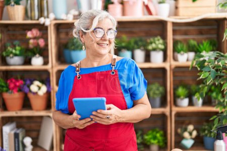 Photo for Middle age grey-haired woman florist smiling confident using touchpad at florist - Royalty Free Image