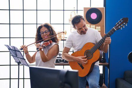 Photo for Man and woman musicians playing violin and classical guitar at music studio - Royalty Free Image