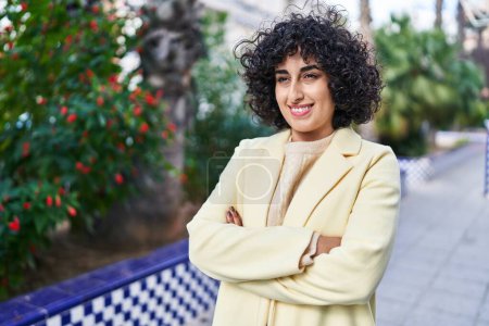 Téléchargez les photos : Jeune femme du Moyen-Orient excutive souriant confiant debout avec les bras croisés geste au parc - en image libre de droit