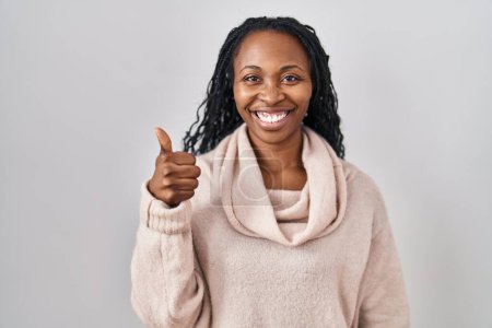 Téléchargez les photos : Femme africaine debout sur fond blanc faisant des pouces heureux geste avec la main. approuvant l'expression regardant la caméra montrant le succès. - en image libre de droit