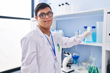 Téléchargez les photos : Homme trisomique portant l'uniforme scientifique tenant le tube à essai au laboratoire - en image libre de droit