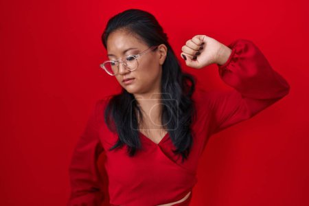 Photo for Asian young woman standing over red background stretching back, tired and relaxed, sleepy and yawning for early morning - Royalty Free Image