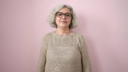 Téléchargez les photos : Femme d'âge moyen avec les cheveux gris debout avec une expression sérieuse sur fond rose isolé - en image libre de droit