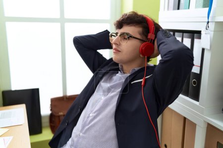 Téléchargez les photos : Non binary man business worker listening to music relaxed at office - en image libre de droit