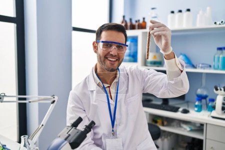 Téléchargez les photos : Jeune homme hispanique scientifique tenant une éprouvette au laboratoire - en image libre de droit