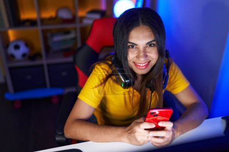 Foto de Young beautiful arab woman streamer using computer and smartphone at gaming room - Imagen libre de derechos