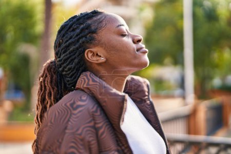 Foto de Mujer afroamericana respirando con los ojos cerrados en el parque - Imagen libre de derechos