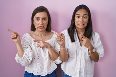 Photo for Hispanic mother and daughter together pointing aside worried and nervous with both hands, concerned and surprised expression - Royalty Free Image