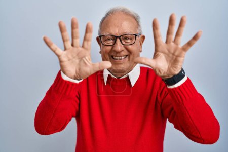 Foto de Hombre mayor con el pelo gris de pie sobre el fondo aislado mostrando y señalando hacia arriba con los dedos número diez mientras sonríe confiado y feliz. - Imagen libre de derechos