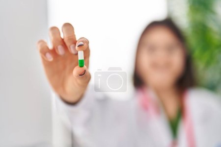 Téléchargez les photos : Jeune belle hispanique femme médecin tenant pilule à la clinique - en image libre de droit