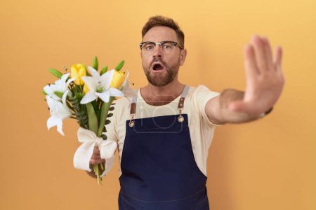 Photo for Middle age man with beard florist shop holding flowers doing stop gesture with hands palms, angry and frustration expression - Royalty Free Image