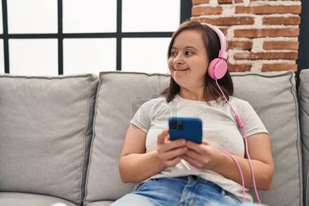 Foto de Down syndrome woman watching video on smartphone at home - Imagen libre de derechos