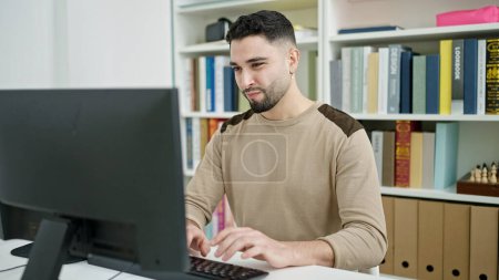 Téléchargez les photos : Jeune homme arabe étudiant à l'aide d'un ordinateur étudiant à l'université - en image libre de droit
