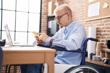 Foto de Joven trabajador de negocios caucásico hombre usando teléfono inteligente sentado en silla de ruedas en la oficina - Imagen libre de derechos