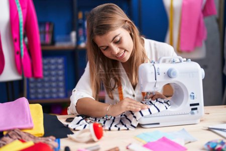 Foto de Young woman tailor smiling confident using sewing machine at sewing studio - Imagen libre de derechos