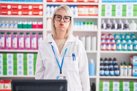 Photo for Young caucasian woman working at pharmacy drugstore puffing cheeks with funny face. mouth inflated with air, crazy expression. - Royalty Free Image