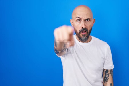 Téléchargez les photos : Homme hispanique avec des tatouages debout sur fond bleu pointant mécontent et frustré à la caméra, en colère et furieux contre vous - en image libre de droit