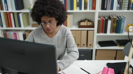 Foto de African american woman student using computer studying at library university - Imagen libre de derechos
