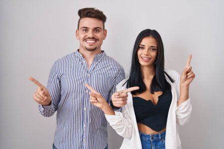Photo for Young hispanic couple standing over white background smiling confident pointing with fingers to different directions. copy space for advertisement - Royalty Free Image