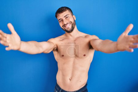 Photo for Handsome hispanic man standing shirtless looking at the camera smiling with open arms for hug. cheerful expression embracing happiness. - Royalty Free Image