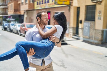 Photo for Man and woman interracial couple holding in arms at street - Royalty Free Image