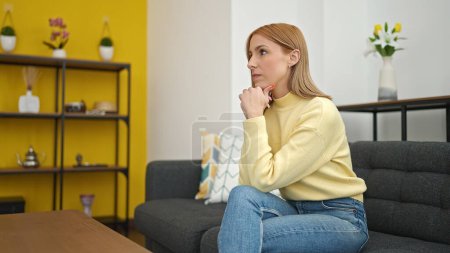Photo for Young blonde woman stressed sitting on sofa at home - Royalty Free Image