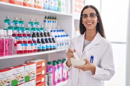 Photo for Young beautiful hispanic woman pharmacist smiling confident working at pharmacy - Royalty Free Image