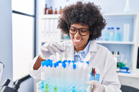 Foto de Mujer científica afroamericana sosteniendo tubos de ensayo en laboratorio - Imagen libre de derechos