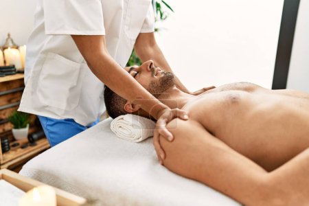 Téléchargez les photos : Deux hommes hispaniques thérapeute et patient ayant massage facial au centre de beauté - en image libre de droit