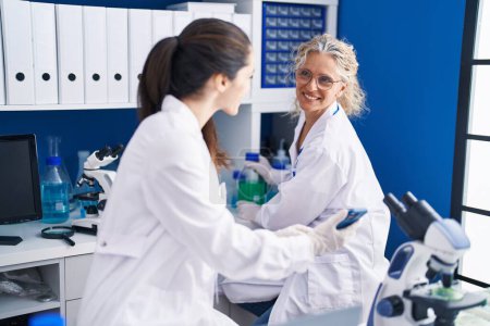 Photo for Two women scientists using smartphone working at laboratory - Royalty Free Image