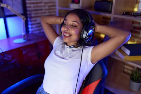 Photo for Young arab woman streamer smiling confident relaxed with hands on head at gaming room - Royalty Free Image