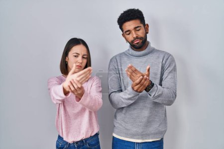 Photo for Young hispanic couple standing together suffering pain on hands and fingers, arthritis inflammation - Royalty Free Image