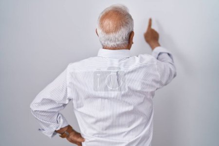 Photo for Senior man with grey hair standing over isolated background posing backwards pointing ahead with finger hand - Royalty Free Image