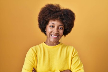 Téléchargez les photos : Young african american woman standing over yellow background happy face smiling with crossed arms looking at the camera. positive person. - en image libre de droit