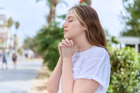 Photo for Young caucasian woman praying with closed eyes at park - Royalty Free Image