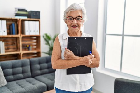 Photo for Senior grey-haired woman psychologist holding clipboard at psychology center - Royalty Free Image