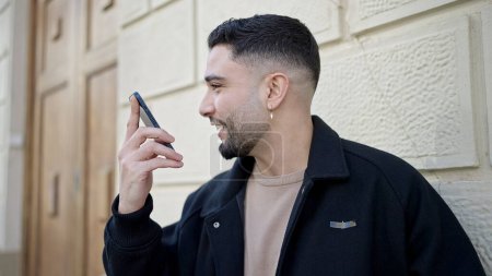 Foto de Hombre árabe joven enviando mensaje de voz con teléfono inteligente en la calle - Imagen libre de derechos
