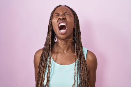 Téléchargez les photos : Femme afro-américaine debout sur fond rose en colère et fou hurlant frustré et furieux, criant de colère. rage et concept agressif. - en image libre de droit