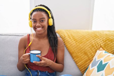 Foto de Mujer afroamericana escuchando música tomando café en casa - Imagen libre de derechos